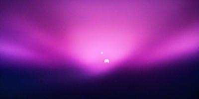 The primary subject of the image is a pink sky with a sun in the middle. The setting is a purple background, which adds a unique visual style to the scene. The colors and mood of the image are predominantly pink and purple, creating a warm and serene atmosphere.
