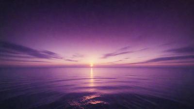 The primary subject of the image is the sunset, with the sun setting over the ocean. The setting is a vast body of water, and the visual style is a photo. The colors and mood of the image are dominated by the warm hues of the sunset, creating a serene and peaceful atmosphere.