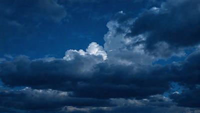 The primary subject of the image is a cloudy sky with a few clouds scattered throughout. The setting is a blue sky, which serves as the backdrop for the clouds. The visual style of the image is a photo, capturing the natural beauty of the cloudy sky. The colors in the image are predominantly shades of blue and gray, creating a calm and serene atmosphere.