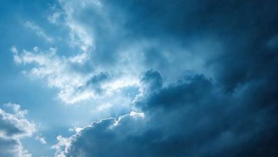 The primary subject of the image is a cloudy blue sky with a few clouds scattered throughout. The setting is an outdoor environment, likely during daytime. The visual style is a natural, realistic representation of the sky. The dominant colors are blue and white, with the blue sky creating a calm and serene atmosphere.