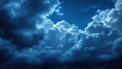 The primary subject of the image is a cloudy blue sky filled with large, fluffy clouds. The setting is a vast, open sky, and the visual style is a natural, outdoor scene. The colors and mood of the image are predominantly blue and serene, creating a peaceful and calming atmosphere.