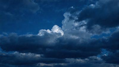 The primary subject of the image is a cloudy sky with a few clouds scattered throughout. The setting is an outdoor environment, possibly during a stormy day. The visual style is a photo of the cloudy sky, capturing the beauty of the clouds and their varying shapes and sizes. The colors and mood of the image are predominantly dark and moody, with the clouds creating a dramatic and ominous atmosphere.