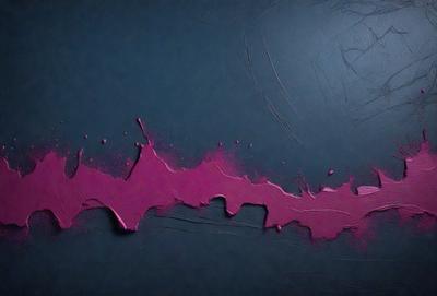 The primary subject of the image is a pink paint splatter on a blue background. The setting is a dark room, and the visual style appears to be a painting or drawing. The colors and mood of the image are predominantly dark and moody, with the pink paint splatter standing out against the blue background.