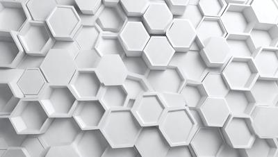 The primary subject of the image is a white wall with a pattern of hexagonal shapes. The setting is a white room, and the visual style is a close-up of the wall. The dominant colors are white, and the overall atmosphere is clean and minimalistic.