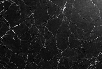 The primary subject of the image is a black marble countertop. The setting is a kitchen, with the countertop being the main focus of the scene. The visual style is a close-up of the marble countertop, showcasing its texture and pattern. The colors and mood of the image are predominantly dark, with the black marble countertop being the main source of contrast.