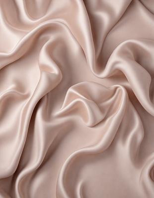 The primary subject of the image is a close-up of a piece of fabric, possibly a silk or satin material. The setting is a white background, which provides a clean and minimalist appearance. The visual style is a close-up of the fabric, showcasing its texture and details. The colors in the image are predominantly shades of pink, which create a warm and elegant atmosphere.