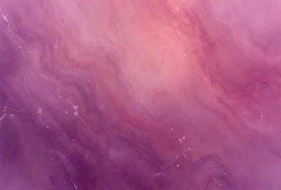 The primary subject of the image is a purple and pink marbled wall. The setting is a room with a pink and purple color scheme. The visual style is a close-up of the marbled wall, showcasing its unique texture and pattern. The colors and mood of the image are vibrant and lively, creating a warm and inviting atmosphere.