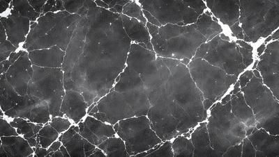The primary subject of the image is a black and white marble pattern. The setting is a black background, which contrasts with the marble pattern. The visual style is a close-up of the marble pattern, showcasing its intricate details. The colors and mood of the image are predominantly black and white, giving it a classic and elegant appearance.
