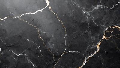 The primary subject of the image is a marble countertop with a black and gold pattern. The setting is a kitchen, and the visual style is a close-up of the marble countertop. The colors and mood of the image are predominantly black and gold, giving it a luxurious and elegant appearance.
