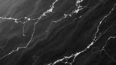 The primary subject of the image is a black marble countertop with a pattern of white veins. The setting is a kitchen, and the visual style is a close-up of the marble countertop. The colors and mood of the image are predominantly black and white, giving it a classic and elegant appearance.