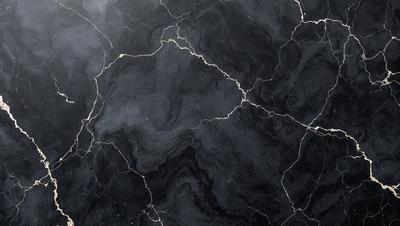 The primary subject of the image is a close-up of a black marble countertop. The setting is a kitchen, with the marble countertop being the main focus of the scene. The visual style is a photo, capturing the intricate details of the marble surface. The colors and mood of the image are predominantly dark, with the black marble providing a striking contrast against the lighter background.