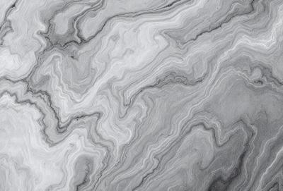 The image features a marble-like surface with a pattern of swirls and waves. The primary subject is the intricate design of the marble, which creates a visually appealing and textured surface. The setting is a gray background that contrasts with the marble, emphasizing its beauty. The visual style is a close-up of the marble, showcasing its unique pattern and texture. The colors and mood of the image are predominantly gray, giving it a calm and sophisticated atmosphere.
