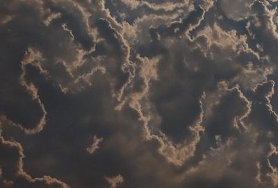 The primary subject of the image is a cloudy sky filled with various cloud formations. The setting is an outdoor environment, with the sky serving as the backdrop. The visual style of the image is a photo, capturing the natural beauty of the cloudy sky. The colors and mood of the image are predominantly dark and moody, with the clouds creating a dramatic and atmospheric scene.