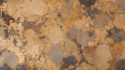 The image features a brown and yellow stone wall with a pattern of holes and bumps. The wall appears to be made of cement or a similar material. The primary subject of the image is the stone wall, which serves as the main object, scene, or focus of the image. The setting/background is the stone wall, and the visual style is a photo. The colors and mood of the image are predominantly brown and yellow, giving it a warm and natural atmosphere.