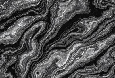 The image features a black and white patterned surface, possibly a marble or stone texture. The primary subject is a close-up of the pattern, which appears to be a combination of swirls and lines. The setting is a dark background, which contrasts with the patterned surface. The visual style is a close-up of the pattern, emphasizing the intricate details of the design. The colors and mood of the image are predominantly dark, with the black and white pattern creating a sense of depth and complexity.