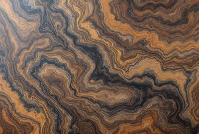 The primary subject of the image is a wooden table with a unique and intricate pattern on its surface. The table appears to be made of wood and has a natural texture. The setting is indoors, with the table being the main focus of the scene. The visual style of the image is a close-up of the wooden table, showcasing its distinctive pattern. The colors and mood of the image are warm and earthy, with the wooden table and its pattern creating a sense of natural beauty and craftsmanship.