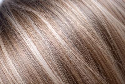 The primary subject of the image is a woman's blonde hair. The setting is a close-up of the hair, with the background being the woman's head. The visual style is a photo, and the colors and mood are predominantly blonde and natural.