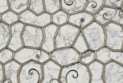 The primary subject of the image is a marble tile with a pattern of swirls and curves. The setting is a white marble surface, which serves as the background. The visual style is a close-up of the marble tile, showcasing its intricate design. The colors and mood of the image are predominantly white, giving it a clean and elegant appearance.