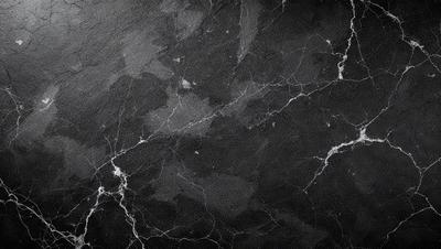 The primary subject of the image is a black marble countertop. The setting is a kitchen, with the countertop being the main focus of the scene. The visual style is a close-up of the marble countertop, showcasing its texture and details. The colors and mood of the image are predominantly dark, with the black marble countertop being the main source of contrast and visual interest.