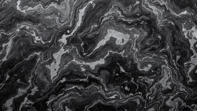 The primary subject of the image is a close-up of a black and white marble surface. The setting is a dark room, and the visual style is a black and white photo. The colors and mood of the image are predominantly dark and moody, with the marble surface being the main focus.