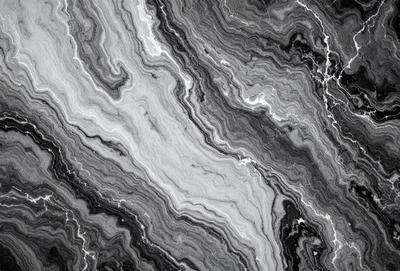 The image features a close-up of a marble surface with a pattern of swirls and stripes. The marble appears to be black and white, giving it a unique and elegant appearance. The pattern of the marble creates a visually striking and textured surface, making it an interesting focal point in the image.