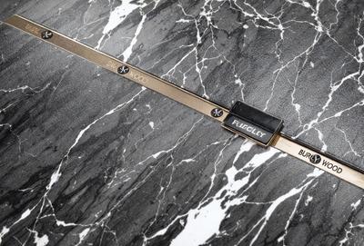 The primary subject of the image is a gold and black watch strap. The setting is a marble countertop, and the visual style is a close-up of the watch strap. The colors in the image are predominantly black and gold, giving the strap a sophisticated and elegant appearance.