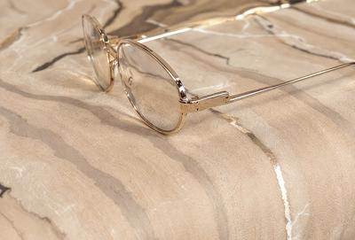 The primary subject of the image is a pair of glasses, which are placed on a marble table. The setting is a marble table, and the visual style is a photo. The colors and mood of the image are predominantly neutral, with the marble table and glasses being the main focus.