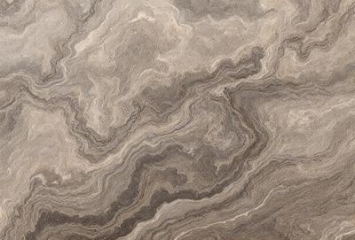 The image features a marble-like surface with a pattern of swirls and waves. The primary subject is the intricate design of the marble, which creates a visually appealing and textured surface. The setting is a natural environment, possibly a stone or marble quarry, where the marble is sourced. The visual style is a close-up of the marble, showcasing its unique patterns and textures. The colors and mood of the image are predominantly earthy tones, such as