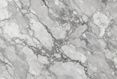 The primary subject of the image is a marble surface with a pattern of holes and grooves. The setting is a stone wall, and the visual style is a close-up of the marble surface. The colors and mood of the image are predominantly gray and white, giving it a clean and elegant appearance.