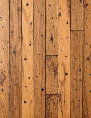 The primary subject of the image is a wooden floor with a pattern of dots. The setting is a room with a wooden floor, and the visual style is a close-up of the wooden floor. The colors and mood of the image are warm and inviting, with the wooden floor being the main focus.