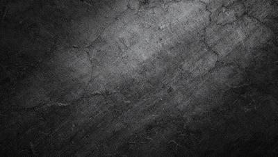 The primary subject of the image is a black and white photo of a wall. The setting is a concrete wall, and the visual style is a black and white photo. The colors and mood of the image are predominantly dark and moody, with the black and white color scheme adding to the atmosphere.