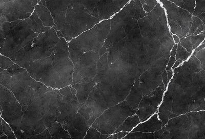 The primary subject of the image is a black and white marble tile. The setting is a black and white marble wall, which serves as the background. The visual style is a close-up of the marble tile, showcasing its texture and pattern. The colors and mood of the image are predominantly black and white, giving it a classic and elegant appearance.