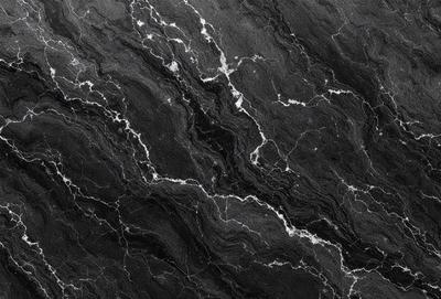 The primary subject of the image is a close-up of a black marble surface. The setting is a dark room, and the visual style is a photo. The dominant colors are black and white, creating a moody atmosphere.