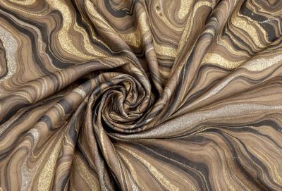 The primary subject of the image is a gold and brown fabric, which appears to be a piece of cloth or a curtain. The setting is a room with a patterned wall, and the visual style is a close-up of the fabric. The colors and mood of the image are warm and cozy, with the gold and brown tones creating a sense of luxury and comfort.