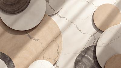 The primary subject of the image is a collection of white and brown round plates. These plates are arranged on a marble surface, which serves as the setting and background of the scene. The visual style of the image is a photo, capturing the details and textures of the plates and the marble surface. The colors and mood of the image are predominantly neutral, with the white and brown tones of the plates and the marble surface creating a clean and elegant atmosphere.