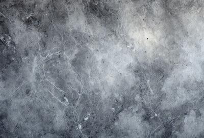 The primary subject of the image is a gray marble wall. The setting is a room with a gray marble wall as the main object. The visual style is a photo, and the colors and mood are predominantly gray and neutral.
