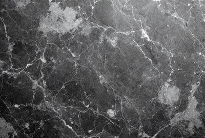 The primary subject of the image is a marble surface with a pattern of holes and ridges. The setting is a black and white photo, which gives the image a classic and timeless appearance. The visual style is a close-up of the marble surface, highlighting the intricate details of the pattern. The colors and mood of the image are predominantly black and white, creating a sense of elegance and sophistication.