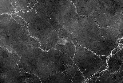 The primary subject of the image is a black and white marble wall. The setting is a dark room, and the visual style is a close-up of the marble wall. The colors and mood of the image are predominantly dark and moody, with the marble wall being the main focus.