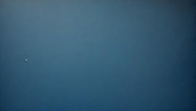 The primary subject of the image is a large, empty blue sky. The setting is a vast, open space with no visible landmarks or objects. The visual style is a simple, uncluttered representation of the sky. The colors and mood are predominantly blue, creating a calm and serene atmosphere.