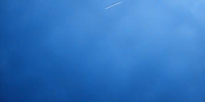 The primary subject of the image is the sky, which is a deep blue color. The setting is a cloudy day, with a few clouds visible in the sky. The visual style of the image is a photo, capturing the beauty of the cloudy blue sky. The colors and mood of the image are serene and peaceful, as the sky is free of any disturbances or pollution.