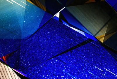 The primary subject of the image is a blue and black patterned surface, which appears to be a piece of art or a decorative item. The setting is a room with a wooden floor, and the visual style is a combination of digital art and illustration. The dominant colors in the image are blue and black, creating a striking and visually appealing atmosphere.