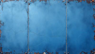 The primary subject of the image is a blue door with a rusted surface. The setting is an outdoor environment, and the visual style appears to be a photo. The dominant colors are blue and rust, creating a mood of aged and weathered materials.
