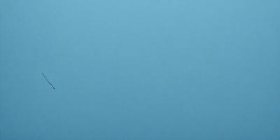 The primary subject of the image is a large, open, and empty blue sky. The setting is a vast, cloudless expanse, with no visible landmarks or objects. The visual style is a natural, untouched landscape, with no indication of digital manipulation or artistic elements. The colors and mood are predominantly blue, conveying a sense of tranquility and vastness.