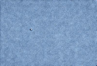 The primary subject of the image is a small white dot, which is located in the middle of a blue surface. The setting appears to be a blue sky, and the visual style is a close-up of the dot on a blue background. The colors and mood of the image are predominantly blue, creating a calm and serene atmosphere.