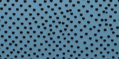 The primary subject of the image is a blue background with a pattern of black dots. The setting appears to be a blue surface, possibly a wall or a piece of fabric. The visual style of the image is a close-up of the blue background with the black dots, which gives it a textured and patterned appearance. The colors and mood of the image are predominantly blue and black, creating a calm and visually striking scene.