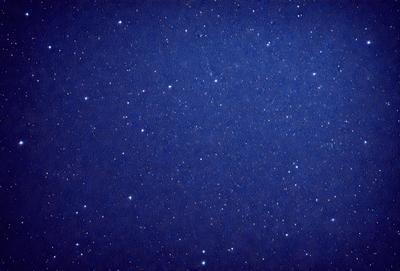 The primary subject of the image is the night sky, which is filled with stars. The setting is a dark, starry background, and the visual style is a photo of the night sky. The colors and mood of the image are predominantly dark and serene, with the stars providing a sense of wonder and tranquility.