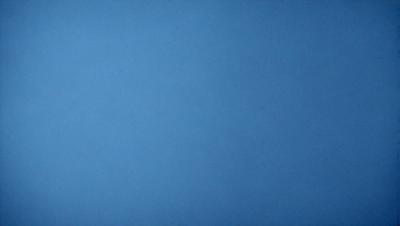 The primary subject of the image is a large, open blue sky. The setting is a vast, cloudless expanse, with no visible landmarks or objects. The visual style is a natural, untouched landscape, with no indication of digital manipulation or artistic elements. The colors and mood are predominantly blue, creating a serene and peaceful atmosphere.
