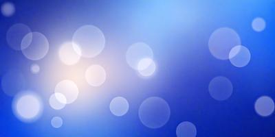 The primary subject of the image is a blue background with a pattern of white circles. The setting appears to be a bright, sunny day, as the sunlight is shining through the circles, creating a visually appealing and lively atmosphere. The visual style of the image is a combination of a photo and digital art, as the circles are arranged in a way that resembles a painting or a digital design. The colors and mood of the image are predominantly blue and bright, with the white circles adding a touch of