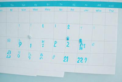 The primary subject of the image is a calendar with blue writing. The setting is a white surface, and the visual style appears to be a hand-drawn illustration. The colors and mood of the image are predominantly blue, creating a calm and organized atmosphere.