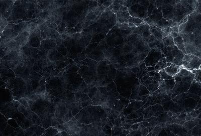 The primary subject of the image is a black and white photo of a galaxy. The setting is a black background, which emphasizes the galaxy's structure and patterns. The visual style is a close-up of the galaxy, showcasing its intricate details. The colors and mood of the image are predominantly dark and moody, with the galaxy's light and patterns creating a striking contrast against the black background.